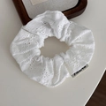 Dettaglio di uno scrunchie in cotone bianco con ricamo floreale e etichetta del logo - Scrunchie Letterario - Piccolo