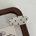Detailed view of an oval polka dot resin hair clip on a natural canvas texture background - Oval Hair Clip / White