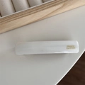 Close-up of cream acetate hair clip with gold France Handmade lettering on wood tray - White