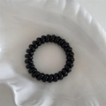 Dettaglio dell'elastico per capelli a spirale nero lucido in un vassoio a conchiglia - Stile Nero (FQ88495) / Nero