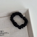 Macro detail of high-density black silk satin scrunchie with smooth pleated texture - Black