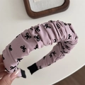 Gros plan d'un serre-tête rose froncé avec motifs nœuds noirs et texture de tissu doux - Serre-tête Rose Nœud - Plissé
