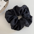 Détail d'un chouchou noir avec motifs nœuds brodés et texture soyeuse de haute qualité - Nœud Noir