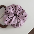 Détail d'un chouchou rose géant à pois noirs avec une texture de tissu plissé et doux - Chouchou Rose - À Pois