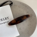 Detail of a brown tortoiseshell hair clip with polished acetate finish on a ceramic plate - Dark Tortoise - Oval Shape