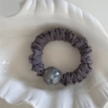 Detail view of dark grey pleated hair scrunchie with a large translucent grey bead decoration - Purple