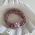 Dettaglio di elastico per capelli a pieghe color malva con perla glitterata in ciotola - Rosa