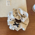 Dettaglio dell'elastico per capelli beige a pois con fiocco e ciondolo di perla - Beige