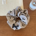 Dettaglio dell'elastico scrunchie a pois con fiocco nero e ciondolo di perla - Marrone