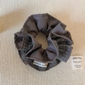 Detail eines grauen Karo-Scrunchies mit handgemachtem Etikett und kleiner Goldglocke - Grauer Karierter Scrunchie