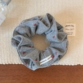 Macro detail van een grijze gebreide scrunchie met rode kersenborduurwerk en handgemaakt label - Grijs Kersborduurwerk