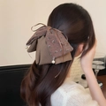 Dettaglio dell'elegante molletta per capelli a fiocco marrone con motivo floreale e perle - Marrone