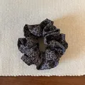 Primer plano detallado de un coletero marrón con flores sobre una alfombra tejida - Coletero Floral de Doble Capa