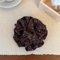 Detail van de donkerbruine scrunchie met blauwe stippen op een zachte achtergrond - Koffie Polka Dot