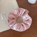 Detail of pink satin scrunchie with soft silk texture and small round metal charm - Pink