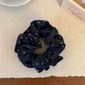 Detailweergave van een zwarte dubbellaagse scrunchie met stippen op een geweven ondergrond - Marineblauw Polka Dot