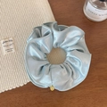Detailed shot of light blue satin oversized scrunchie with a gold logo tag - Light Blue Zircon