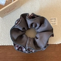 Dettaglio di uno scrunchie a quadri grigi in tessuto twill su una base di legno - Rosso Grigio