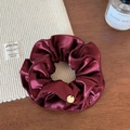 Détail du chouchou en satin bordeaux avec plis superposés et pendentif doré sur bois - Bordeaux