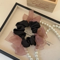 Detail eines eleganten Satin-Haargummis mit drei rosa Organzaschleifen auf einem Tablett - Schwarz