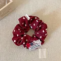 Dettaglio di elastico rosso a pois con bottoni fatti a mano su un tappetino beige - Grandi Pois Rossi