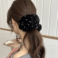 Detailopname van zwarte fluwelen scrunchie met hartpatronen en Love-label in het haar - Hart Stippen Scrunchie