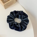 Detail eines dunkelblauen gestreiften Strick-Scrunchies auf weißem Tisch mit Dekobox - Marineblau