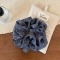 Detailansicht von dunkelblauem Haargummi mit Polka Dots und geschichteter Textur auf Holz - Blau