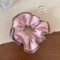 Detail van roze gerimpelde scrunchie met bruine geribbelde randen op warme achtergrond - Roze