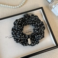 Detail eines floralen Stoff-Haargummis mit Hand Made Label auf einem Luxus-Tablett - Schwarz Blumen Scrunchie