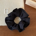 Detail of black pleated fabric scrunchie with vertical texture on a rustic wooden background - Black