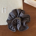 Detail of a dark grey pleated scrunchie with fine texture on a dark wood background - Gray