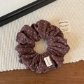 Dettaglio dell'elastico in velluto marrone a fiori con etichetta Hand Made - caffè