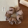 Detailed view of coffee brown ruffled scrunchie with textured fabric on a wooden table - Light Coffee