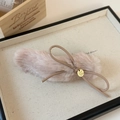 Détail d'une pince à cheveux nœud en peluche avec breloque dorée et simili cuir - Rose
