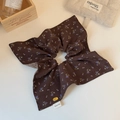 Détail d'un chouchou vintage à fleurs avec étiquette faite main et breloque dorée - Tissu floral café