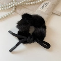 Détail d'un chouchou en peluche noire avec nœud élégant sur un fond blanc minimaliste - Nœud en Peluche Noir