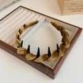 Detail of velvet braided headband with anti-slip inner teeth on wooden display stand - Yellow