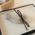 Détail de la pince à cheveux en fourrure beige avec nœud en cuir marron et pendentif doré - Blanc Cassé