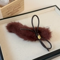 Detailed close-up of plush burgundy hair clip with leather bow and golden label - Red