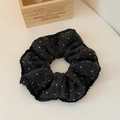 Detail of black polka dot knitted scrunchie with ruffled pleats on a minimal background - Black