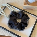 Détail d'un chouchou en satin noir avec bordure en mesh pailleté argenté sur plateau - Noir Dentelle Maille