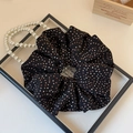 Detail eines schwarzen gepunkteten Haargummis mit Perlenkette in klassischem Ambiente - Schwarzer Polka Dot