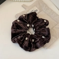 Close-up of a brown velvet polka dot scrunchie on a linen mat with pearl decor - Coffee Polka Dot