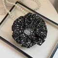 Primo piano di un elastico per capelli a fiori in una scatola con perle - Doppio Strato Nero Floreale