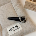 Detail of a black satin heart hair clip with sparkling rhinestones on a linen cushion - Heart Rhinestone Style