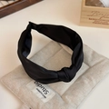 Detail of a black knotted satin headband on a neutral linen cushion with studio props - Black