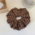 Gros plan détaillé du chouchou géant en tissu marron à motif cachemire sur surface blanche - Marron