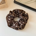 Dettaglio ravvicinato di elastico scrunchie marrone vintage con motivi floreali bianchi - Caffè Floreale