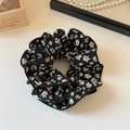 Dettaglio della trama di elastico per capelli floreale nero con stampa bianca su legno - Nero Floreale